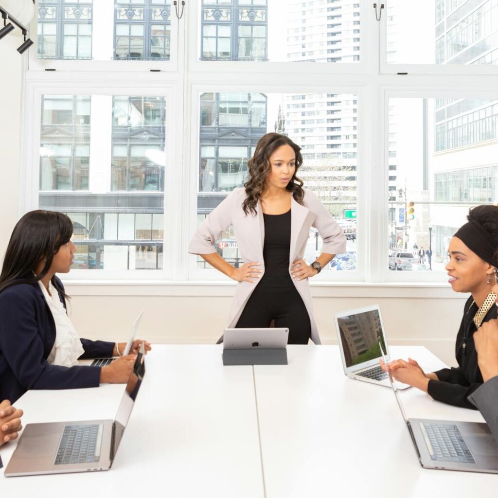 A diverse group of professionals engaged in a meeting at a modern office with laptops and city view.