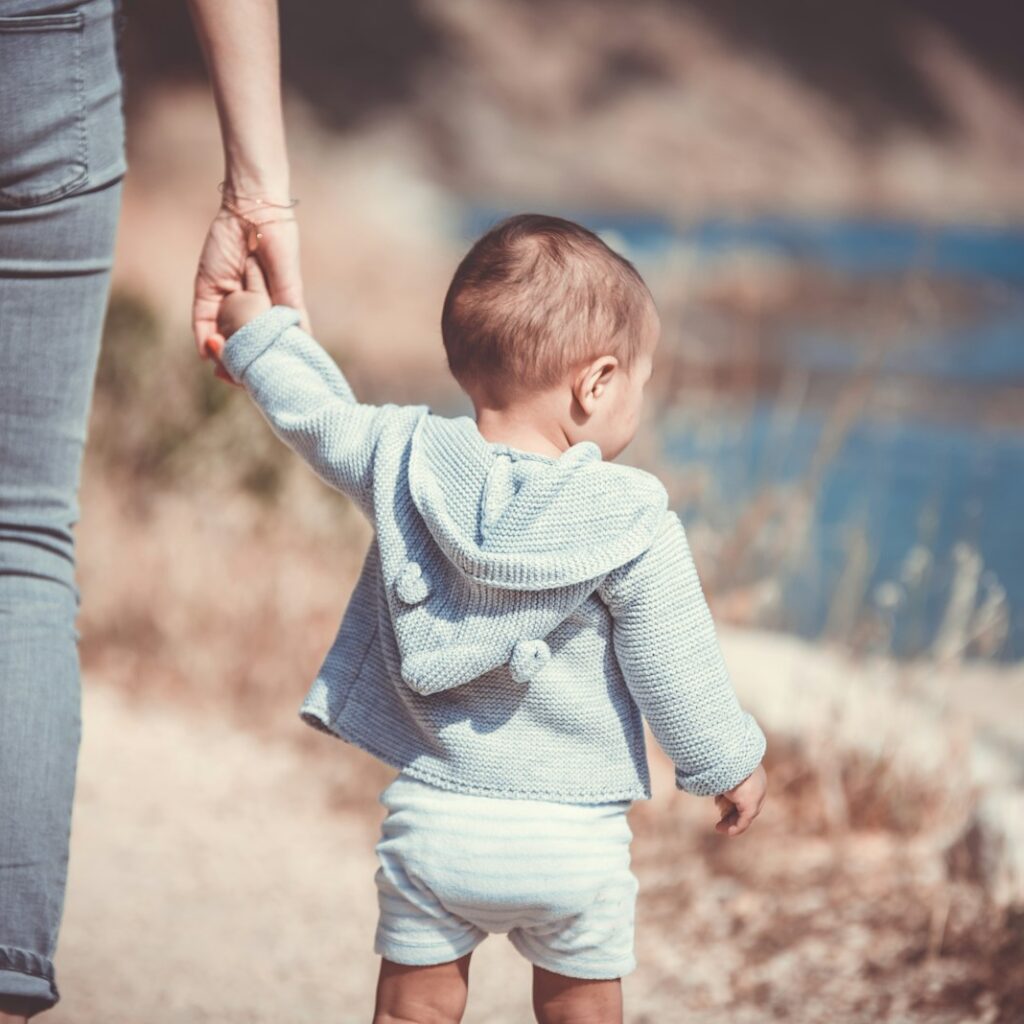 toddler's walking on the seashore with adult